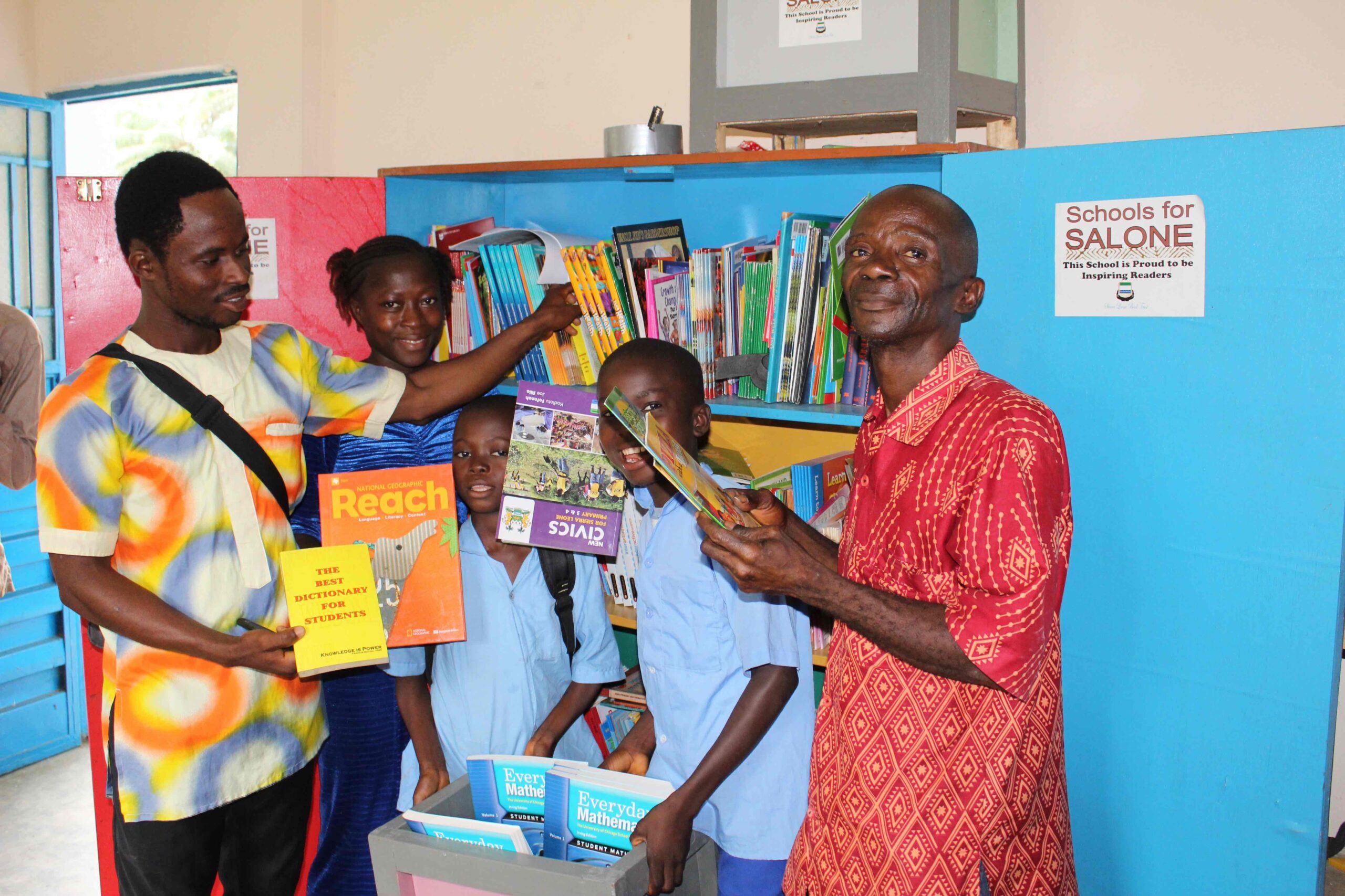 Students and library partners sharing books in a Sierra Leone community library.