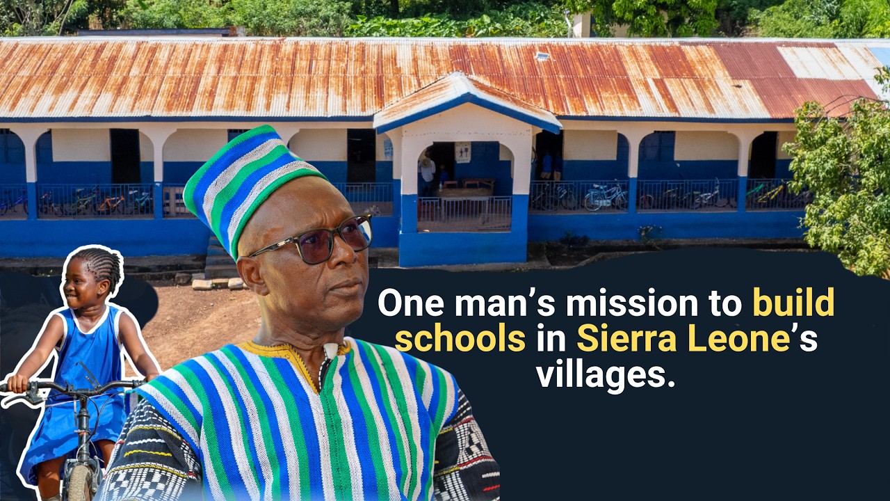 Clinton Caulker standing in front of a school built for a rural Sierra Leone community.